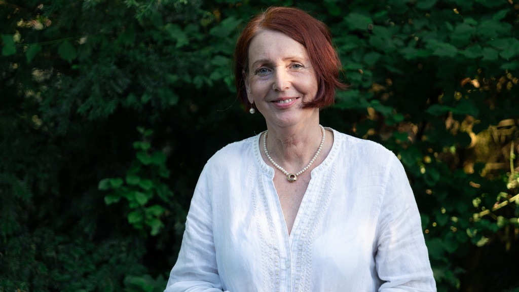 Mareike steht vor einer Hecke und lächelt.